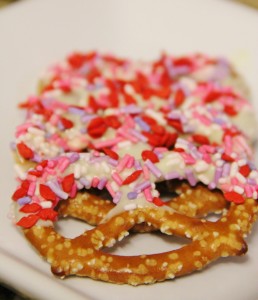 white chocolate dipped pretzels with pink and red sprinkles