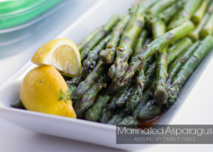 Marinated Asparagus on a platter with lemon wedges