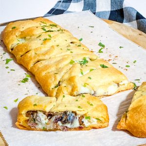 Steak & Provolone Crescent Braid on parchment paper on a pizza peel